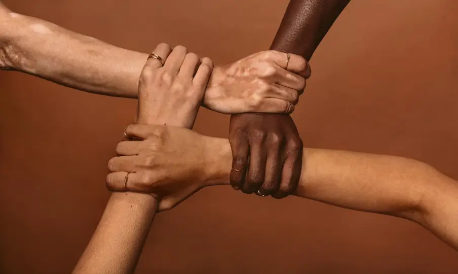 Four hands clasped together representing the Greater Good Youth Organization's commitment to community partnership and inclusive employment